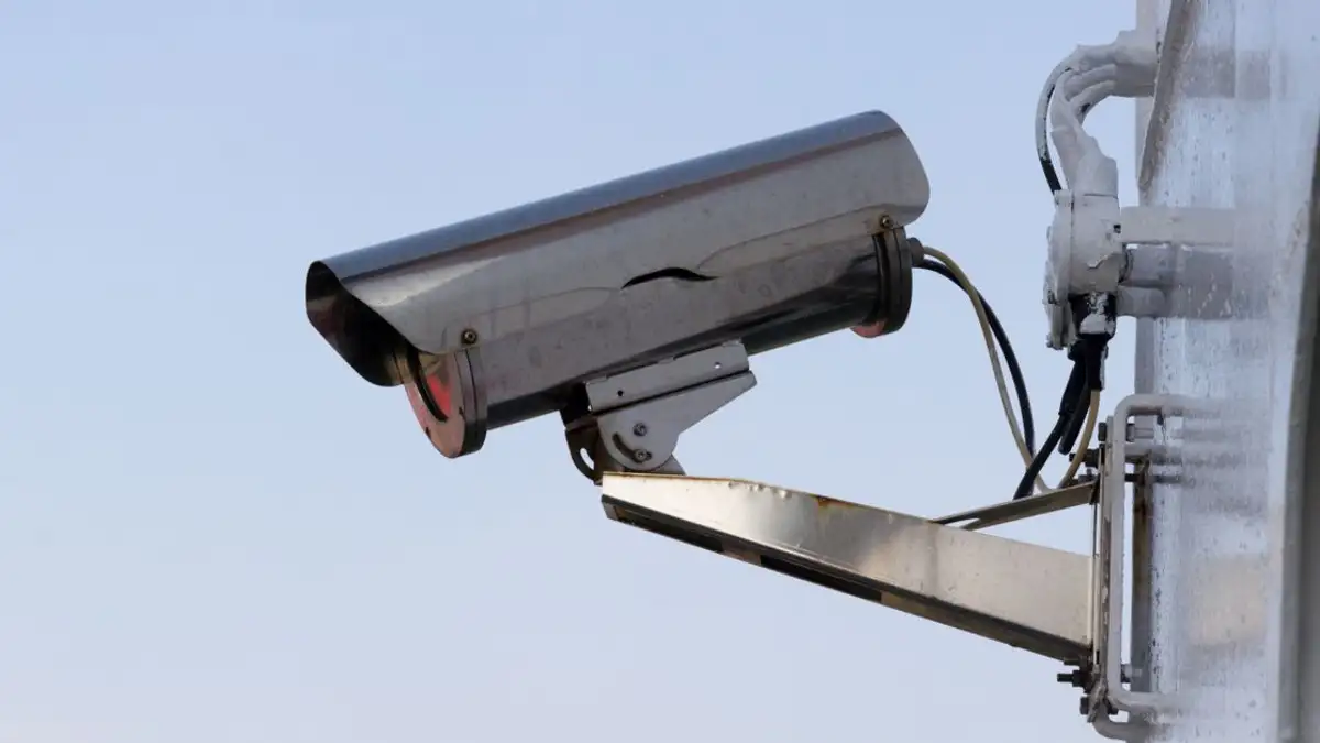 Close-up kamera CCTV luar ruangan yang dipasang di dinding untuk tujuan keamanan.