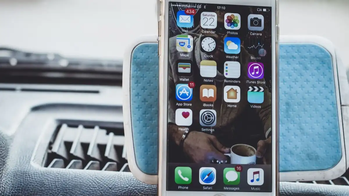 Close-up smartphone yang dipasang di dasbor mobil menunjukkan layar beranda dengan aplikasi.