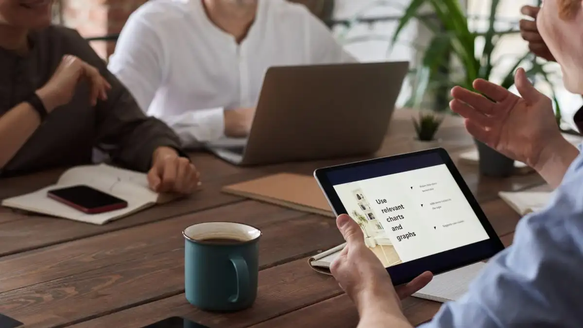 Profesional terlibat dalam pertemuan kolaboratif dengan alat digital, mendorong kerja sama tim dan inovasi.