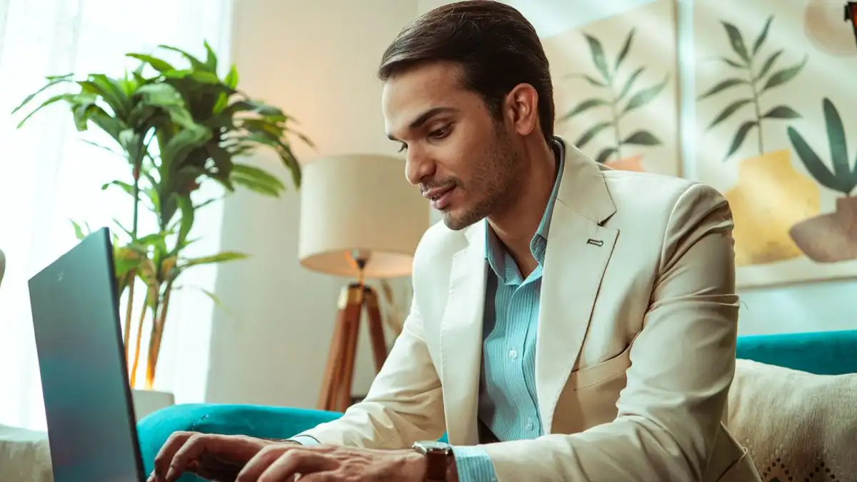 Seorang pebisnis bekerja menggunakan laptop di lingkungan kantor rumahan modern, menampilkan gaya hidup kerja jarak jauh.