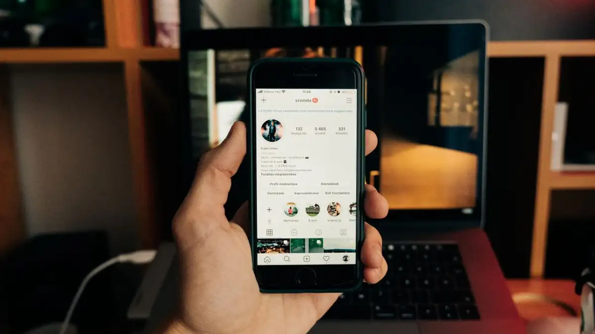 Close-up tangan yang memegang smartphone dengan Instagram terbuka, menampilkan teknologi yang sedang digunakan.