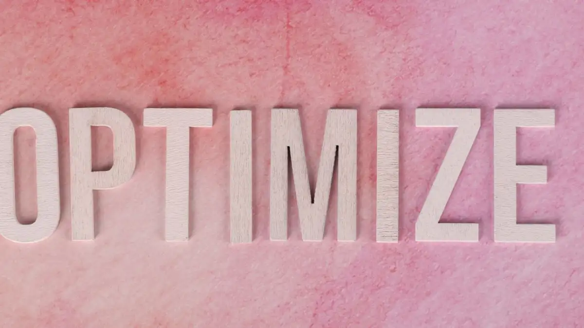 Tampilan kreatif kata 'OPTIMIZE' pada permukaan bertekstur merah muda.