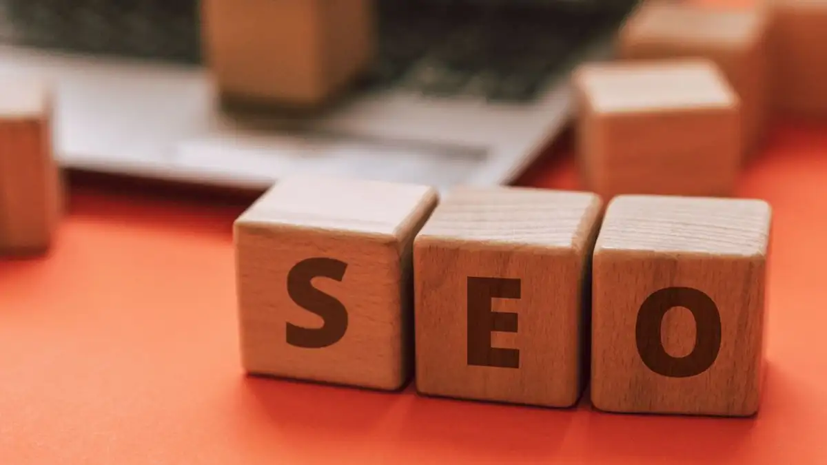 Blok kayu yang mengeja SEO di keyboard laptop menyampaikan konsep pemasaran digital.
