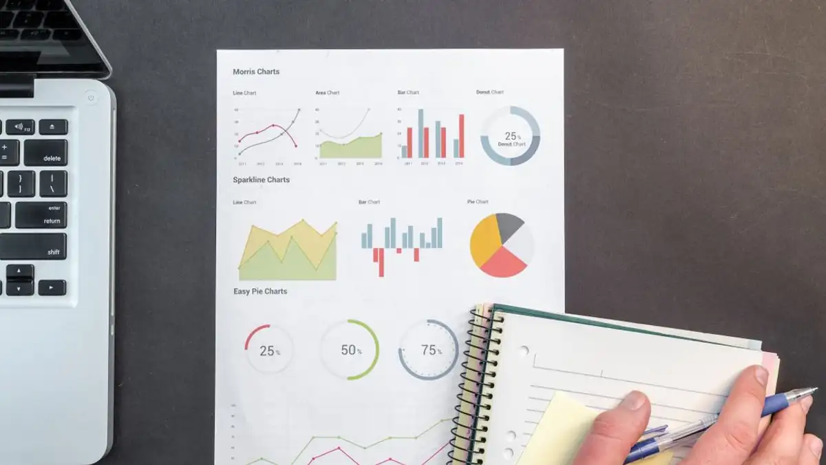 Tampilan dari atas meja bisnis dengan grafik dan laptop, ideal untuk konsep analisis data.