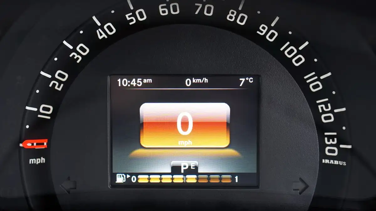 Foto dekat dashboard mobil mewah dengan tachometer digital dan fitur desain yang ramping.