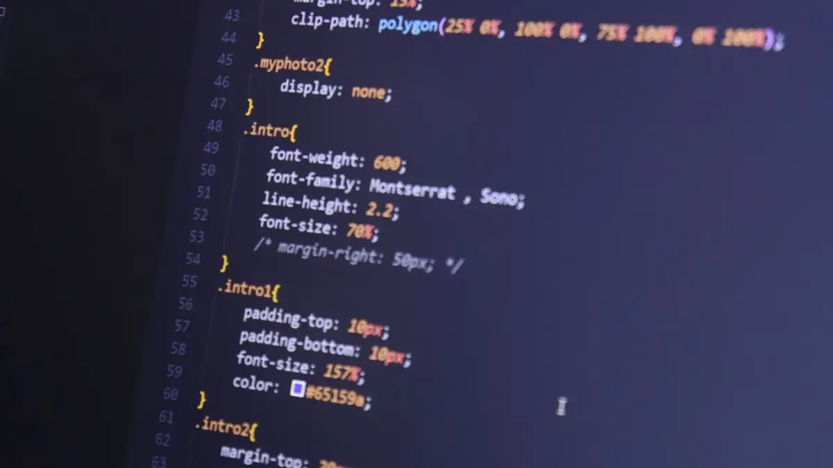 Pengambilan gambar fokus kode HTML dan CSS di monitor untuk pengembangan web.
