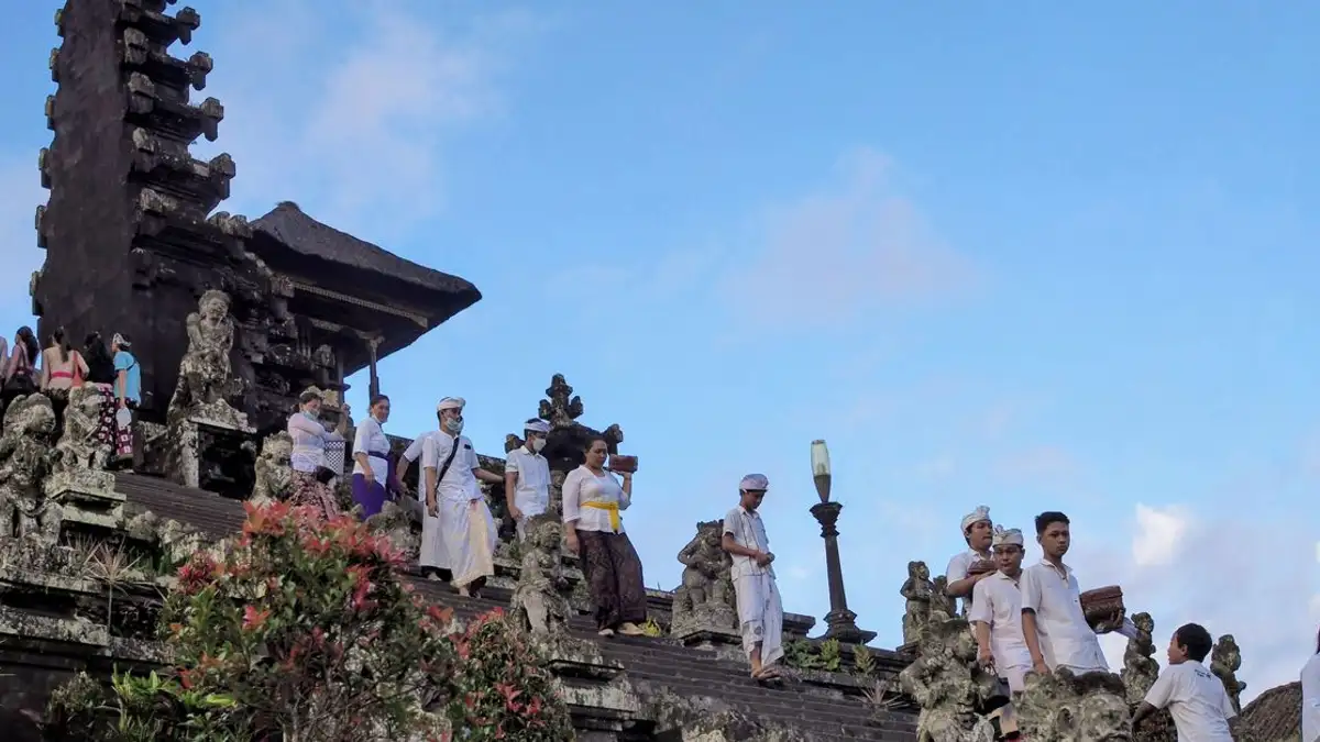 Orang-orang dengan pakaian tradisional di Candi Besakih yang ikonik di Bali, Indonesia, selama upacara budaya.