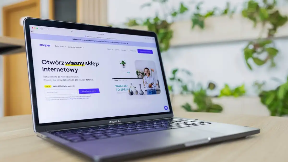 Dekat laptop dengan situs e-commerce terbuka, dikelilingi oleh dekor kantor modern.