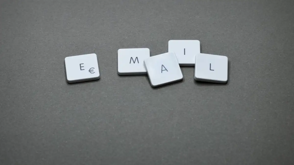 Dekat kata 'email' yang dibentuk dengan ubin huruf di permukaan abu-abu.