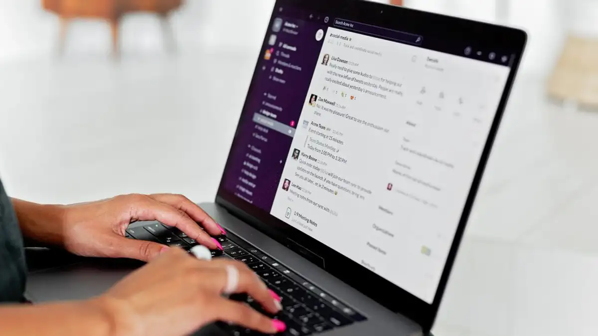 Seorang wanita mengetik di laptop menggunakan aplikasi pesan di pengaturan kantor modern.
