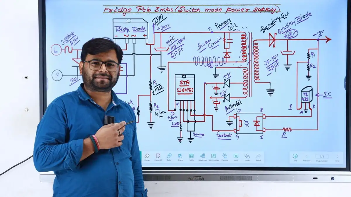 Instruktur di New Delhi mengajar elektronika dengan diagram rangkaian di layar.