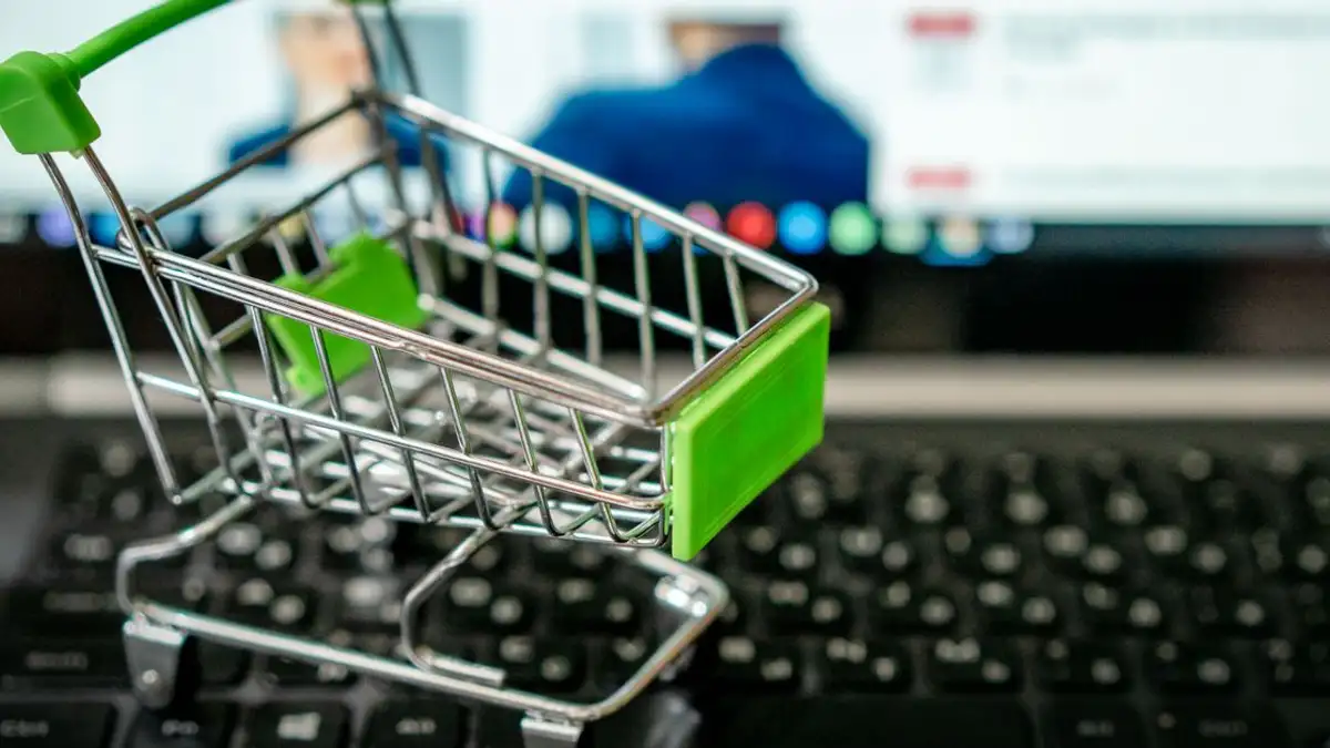 Keranjang belanja mini yang diletakkan di atas keyboard laptop, melambangkan belanja online.