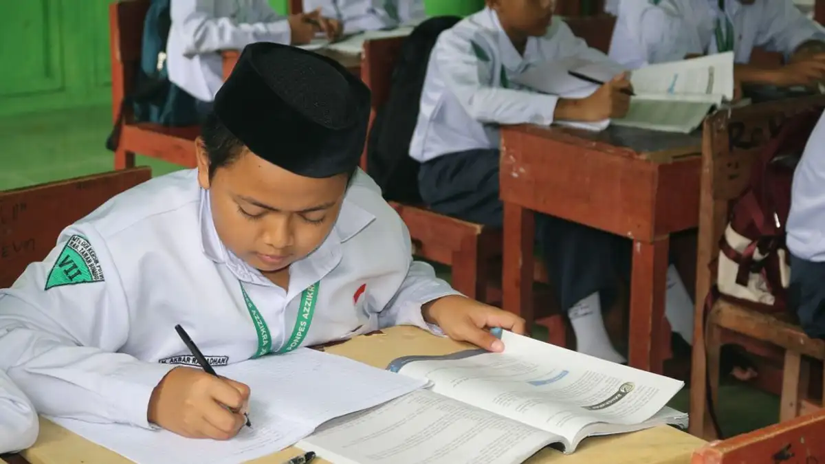 Siswa yang menulis dan belajar dalam lingkungan kelas yang fokus.